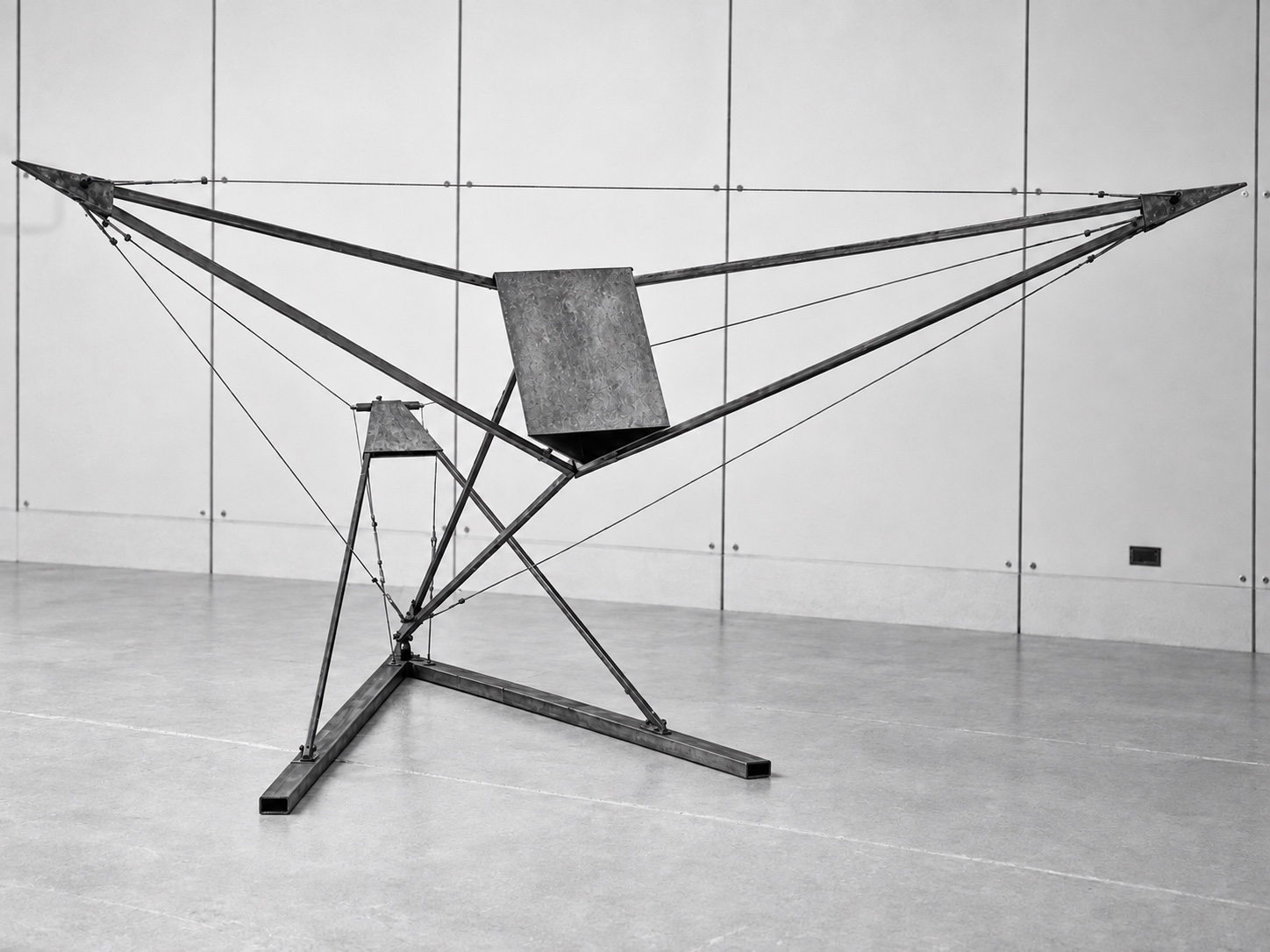 Steel and wire sculpture with wide horizontal arms, a central panel, and crossing supports