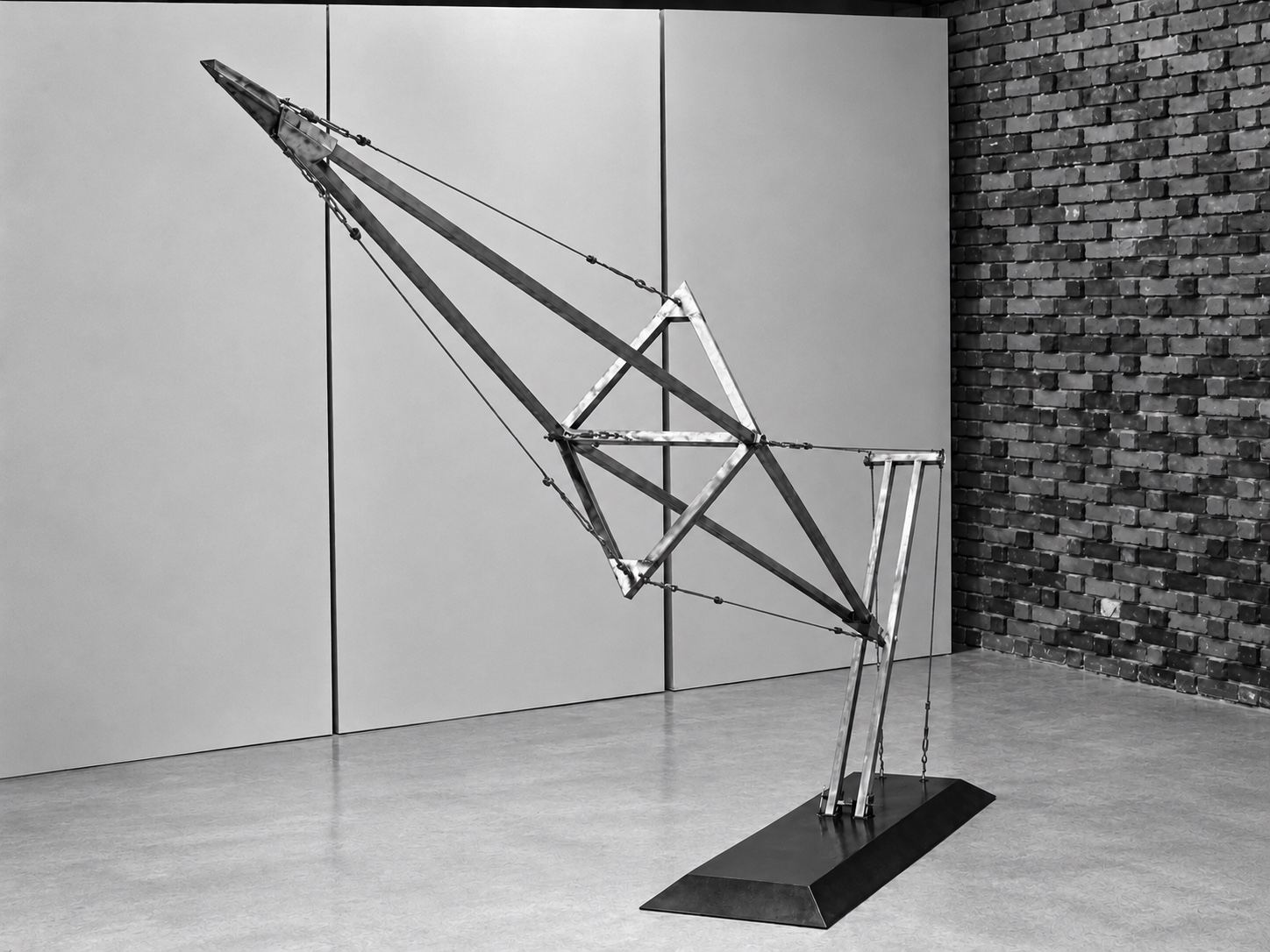Steel and wire sculpture with angled beams, suspended cables, and a rectangular base